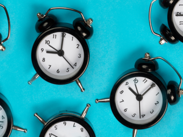 Flat lay of several alarm clocks with blue background