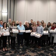 Group of employees holding white boxes, celebrating years of service